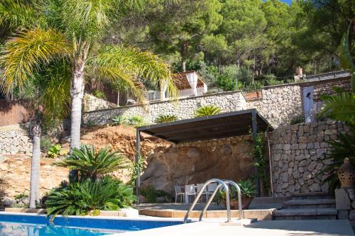 un complejo con piscina y palmeras en Villa Can Rasca en Caimari