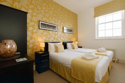 Cette chambre comprend 2 lits et une fenêtre. dans l'établissement Beachcomber - Aldeburgh Coastal Cottages, à Aldeburgh