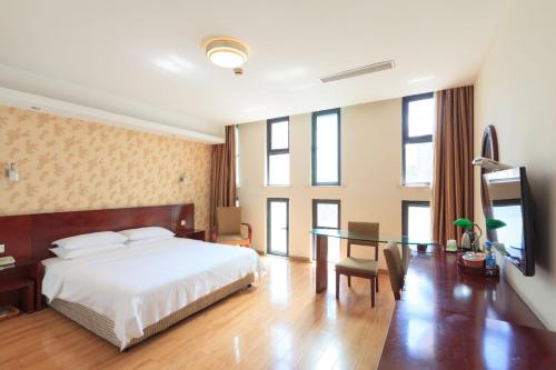 een slaapkamer met een bed, een bureau en een televisie bij Milo Hotel - Near Shanghai Hongqiao National Exhibition Center in Shanghai