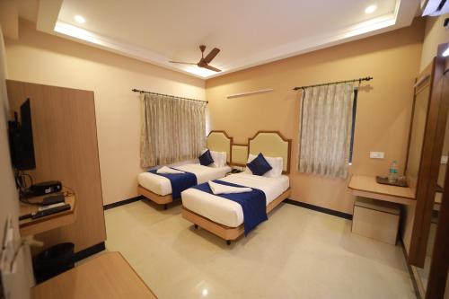 a hotel room with two beds and a television at Majestic Hotel in Madurai