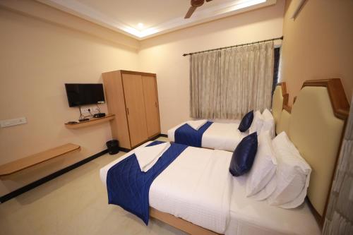a bedroom with two beds with blue pillows at Majestic Hotel in Madurai