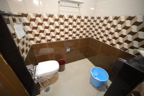 a bathroom with a toilet and a tiled wall at Majestic Hotel in Madurai