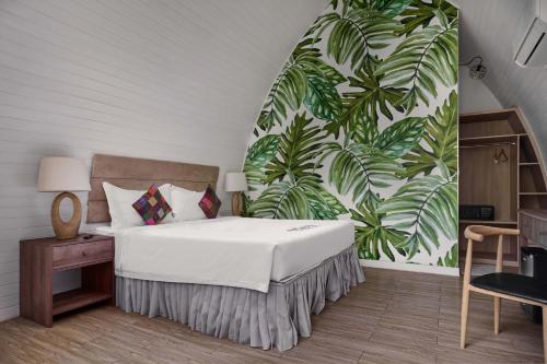 a bedroom with a bed with a tropical wallpaper at Eden Beach Resort By EHM in Koh Rong Sanloem