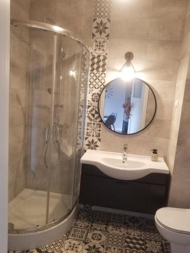 a bathroom with a shower and a sink and a mirror at FORT Apartament in Malbork