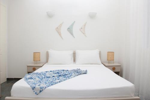ein weißes Bett mit einer blau-weißen Decke darauf in der Unterkunft Aura Paros in Logaras