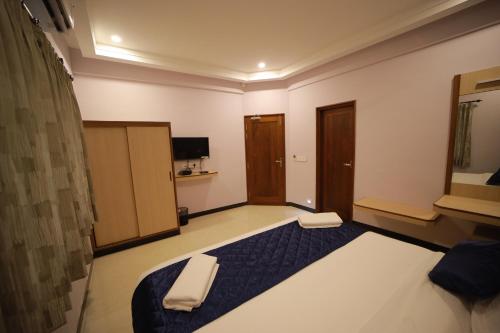 a bedroom with a large bed and a tv at Majestic Hotel in Madurai
