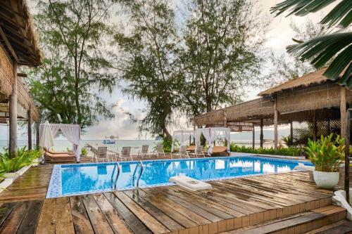 a swimming pool on a wooden deck next to the ocean at Eden Beach Resort By EHM in Koh Rong Sanloem