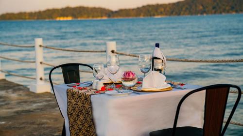 a table with wine glasses and napkins on the water at Eden Beach Resort By EHM in Koh Rong Sanloem