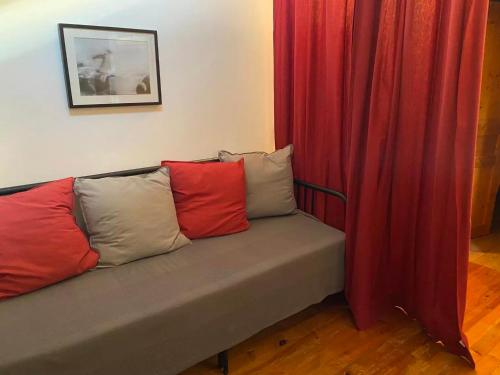 a couch with three pillows sitting next to a red curtain at L'hébergerie sablotine in Chaillé-les-Marais
