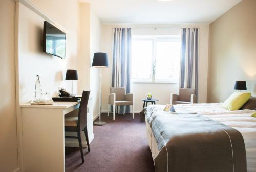 a hotel room with two beds and a desk at Landhotel zum grünen Kranze in Espelkamp-Mittwald