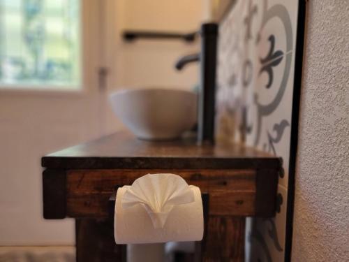 a toilet paper roll on a wooden table with a sink at Sneaky Tiki: Heated Saltwater Pool+5 min to beach in Largo