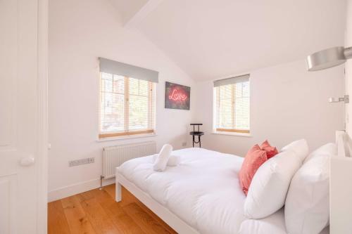 a white bedroom with a white couch and two windows at Windsor Gem: 1-Bed Oasis Near Castle in Windsor