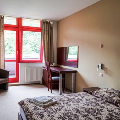 a hotel room with a bed and a desk and a window at Hotel Belaria Resort in Opava