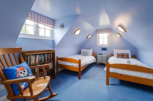 a attic room with two beds and a book shelf at 2 Ogilvie Lodge in Thorpeness
