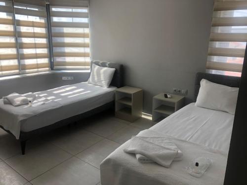 a room with two beds and two windows at ÇALIŞKANLAR OTEL in Canakkale
