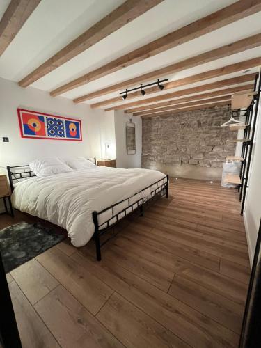 une chambre avec un grand lit et un mur en pierre dans l'établissement La Botte, à Épinal
