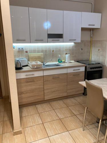 a kitchen with white cabinets and a sink and a table at Center One Apartman in Debrecen