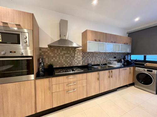 a kitchen with wooden cabinets and stainless steel appliances at Golf view Villa with Jacuzzi- By AppartAli in Bouskoura