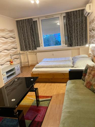 a bedroom with a bed and a couch and a tv at Center One Apartman in Debrecen