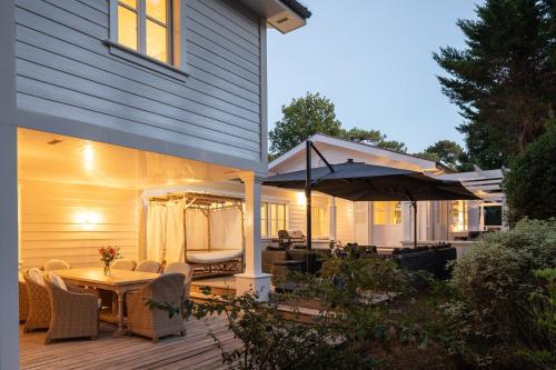 un patio avec une table, des chaises et un parasol dans l'établissement Villa Maison blanche, Arenal, à La Baule