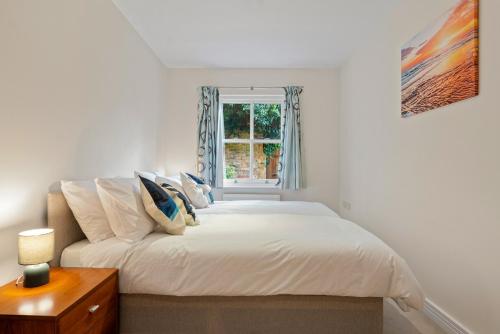 a white bedroom with a bed and a window at Molesey Apartments in East Molesey