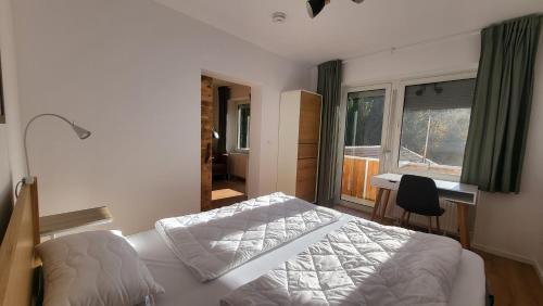 Schlafzimmer mit einem Bett, einem Schreibtisch und einem Fenster in der Unterkunft Ferienwohnung Berglodge 11 Hahnenklee Bockswiese in Goslar