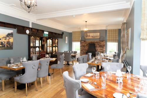 a restaurant with wooden tables and chairs and a fireplace at The Finch Hatton Arms in Sleaford