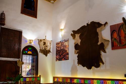 a room with a wall with paintings and a window at Riad Hamad Tijani in Fès