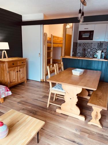uma sala de estar com uma mesa de madeira e uma cozinha em Magnifique studio 4 pers avec balcon vue montagne em Orcières