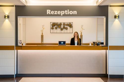 a woman sitting at a reception desk in a lobby at Hotel Newton Heilbronn in Heilbronn
