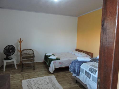 a small bedroom with two beds and a chair at Casa de Campo Chalé Saturno in Alto Paraíso de Goiás