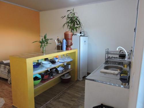 a kitchen with a yellow counter and a refrigerator at Casa de Campo Chalé Saturno in Alto Paraíso de Goiás