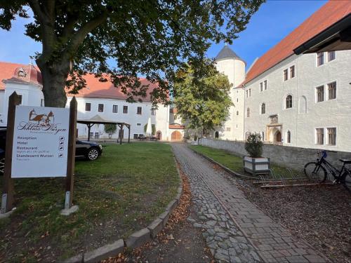 a sign in front of a building with a tree at Schloss Hotel Wurzen in Wurzen