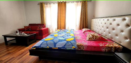 a bedroom with a bed and a chair and a table at HOTEL HUMA in Srinagar