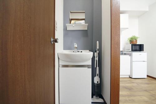 La salle de bains est pourvue d'un lavabo blanc à côté d'une porte. dans l'établissement SUNRISE, à Tokyo