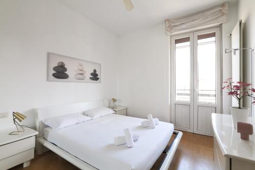 a white bedroom with a white bed and a window at PrimoPiano - Carlone in Milan