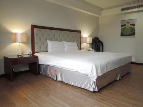 a bedroom with a large white bed and a nightstand at CHECK inn Taipei Neihu in Taipei
