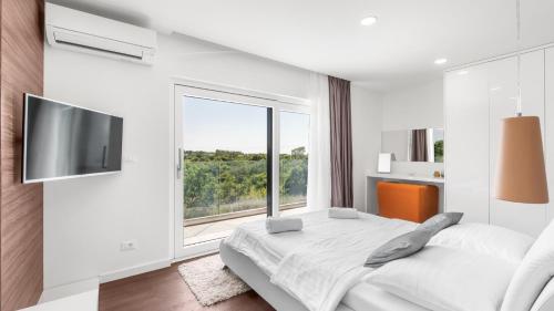 a white bedroom with a bed and a large window at Villa Chic by Villas Holiday in Umag