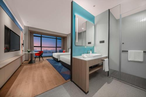 a bathroom with a sink and a bedroom with a bed at Holiday Inn Express Shantou Chenghai in Shantou