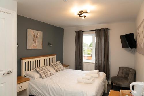 um quarto com uma cama, uma cadeira e uma janela em The Finch Hatton Arms em Sleaford