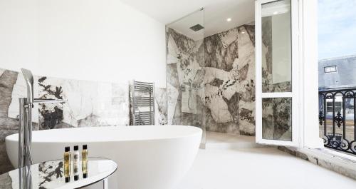 a bathroom with a white tub and a large window at Grand Hôtel Du Palais Royal in Paris