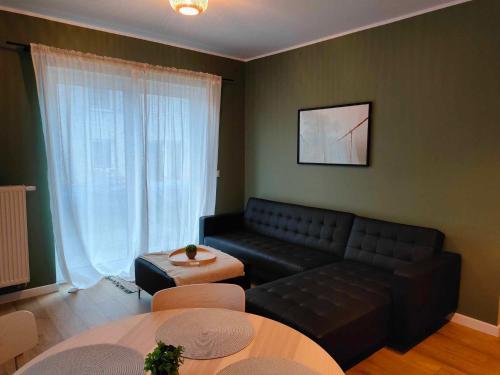 uma sala de estar com um sofá preto e uma mesa em Apartament Margarita em Kudowa-Zdrój