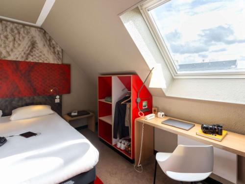 a bedroom with a bed and a desk and a window at ibis Epernay Centre Ville in Épernay