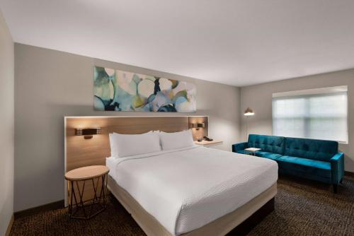 a hotel room with a bed and a blue couch at Wyndham Garden Galena Hotel & Day Spa in Galena