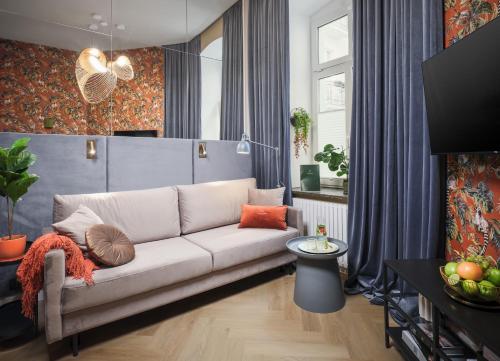 uma sala de estar com um sofá branco e cortinas azuis em Hidden Garden Apartments em Lódź