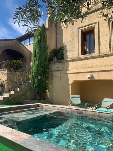 une piscine avec deux chaises et un bâtiment dans l'établissement Maison uzès piscine plein sud avec superbe vue, à Saint-Maximin