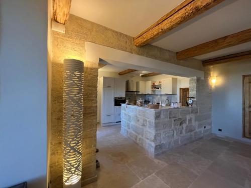 a living room with a stone wall and a kitchen at Maison uzès piscine plein sud avec superbe vue in Saint-Maximin