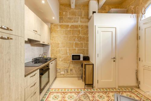 uma cozinha com electrodomésticos brancos e uma parede de tijolos em Authentic 2BR House of Character with Terrace by 360 Estates em Naxxar