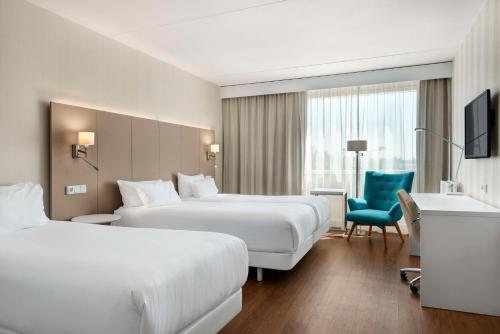 霍夫多普的住宿－阿姆斯特丹史基浦機場NH酒店，酒店客房,设有两张床和一张蓝色椅子