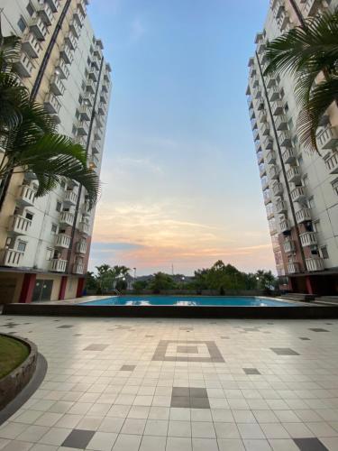 a courtyard between two tall buildings with palm trees at Cibubur Village Apartemen by Ar-Ramadhan in Cibubur